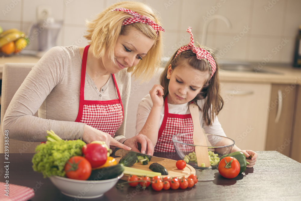 Mother and daughter cutting vegetables