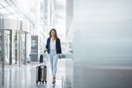 Young businesswoman walking with luggage at airport photo