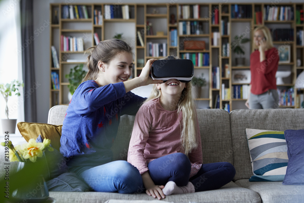 Sisters sitting on couch, playing with VR glasses Sisters sitting on couch, playing with VR glasses