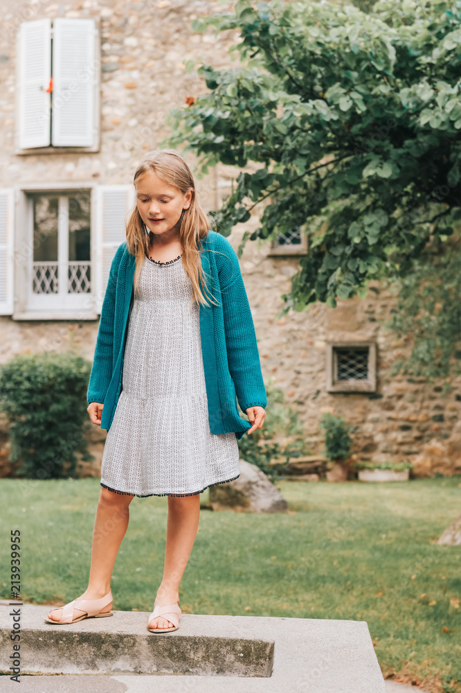 Outdoor portrait of adorable little girl playing in beautiful garden,  wearing summer dress, sandals and green cardigan Stock Photo | Adobe Stock