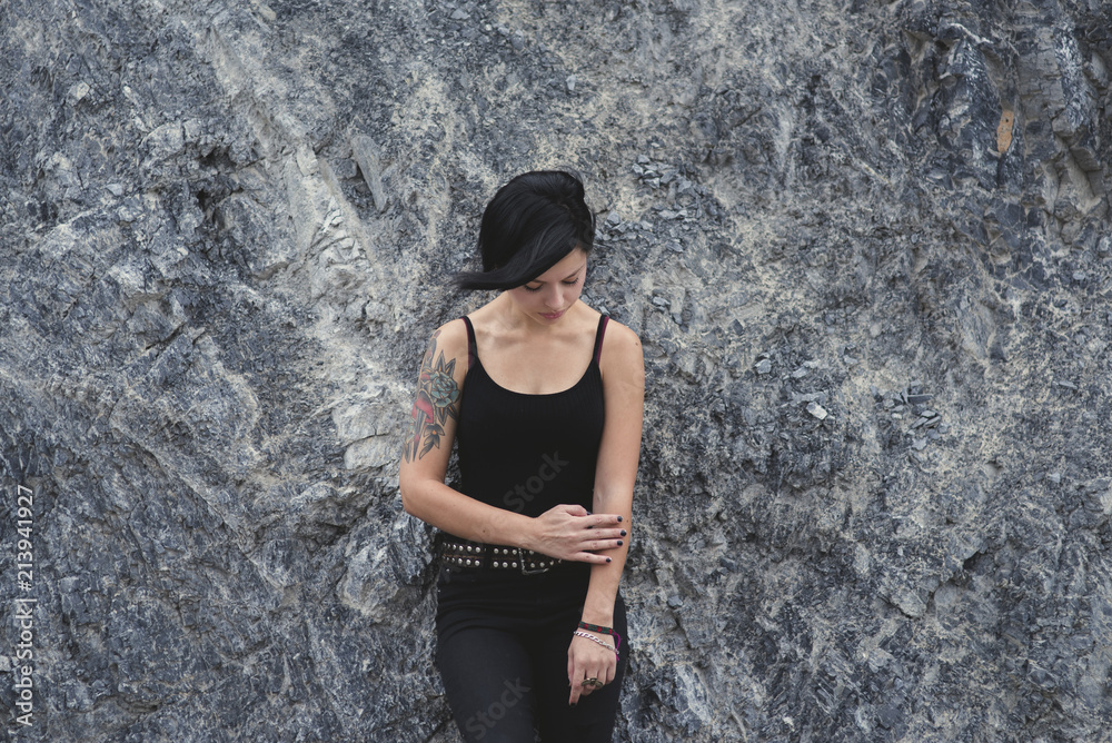 beautiful brunette short hair girl leaning against gray rock wall beautiful brunette short hair girl leaning against gray rock wall
