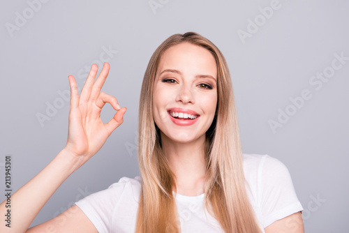 Close up portrait of attractive happy woman with beaming smile, clean skin and smooth straight blonde hair isolated on grey background