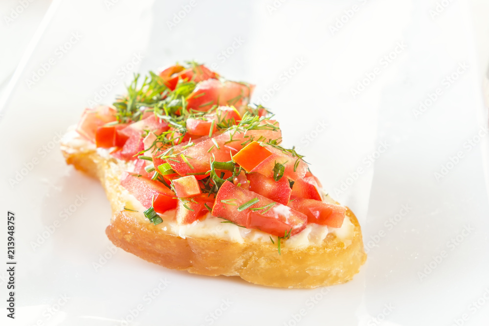 Bruschetta with fresh tomatoes and cheese on a white plate. Close-up