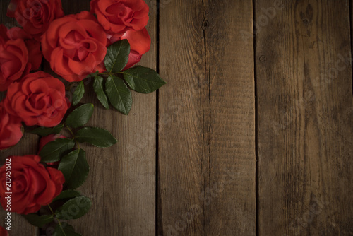 Fototapeta Naklejka Na Ścianę i Meble -  Red roses on a wooden table, background with flowers. Flat lay, top view.