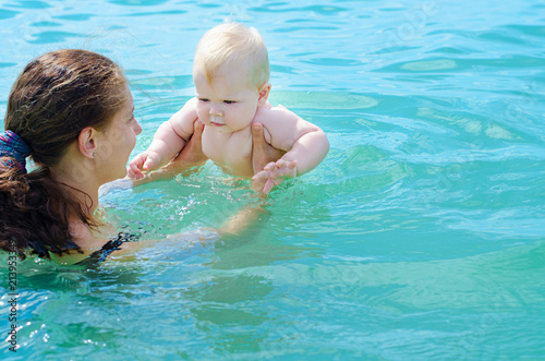 Mother bathing her baby in azure sea water