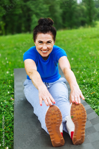 Happy Senior woman doing stretching exercises in park photo