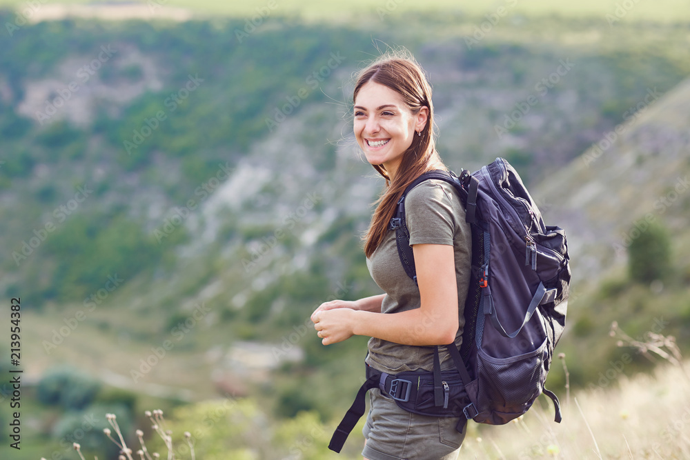 Naklejka premium Happy girl tourist with a backpack smiling in the nature.
