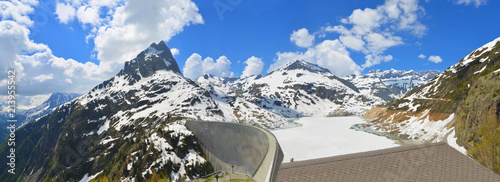 Spectacular view of the Swiss Alps  upfront - Mont Blanc region from Emosson Dam. The Frozen lake Emosson, brilliant blue sky & pristine white clouds add to the stunning wide panoramic view.  