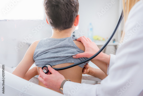 Pediatrician examining boy with stethoscope photo