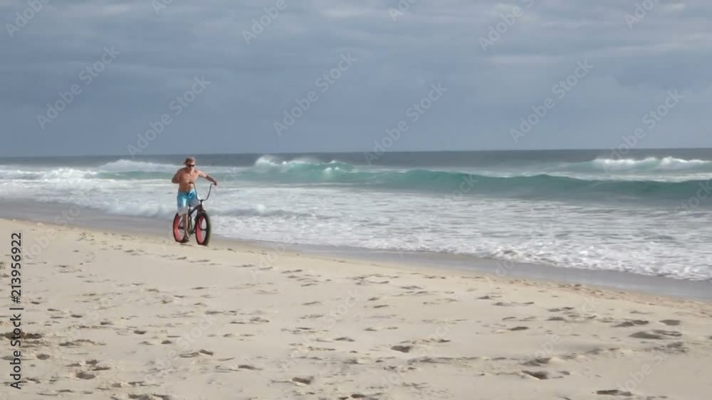 fit man bike riding on gold coast australia beach fit man bike riding on gold coast australia beach