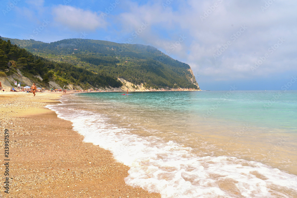paradise sand beach, blue cloudy sky, seascape and waves in Sirolo , Marche, Italy