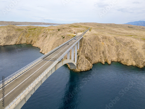 Vista aerea del ponte dell’isola di Pag, Croazia, strade e costa croata. Scogliera a picco sul mare. Auto che attraversano il ponte viste dall’alto © Naeblys