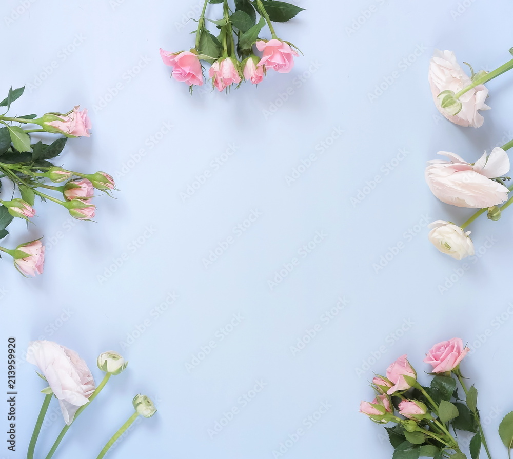 Fototapeta premium Flowers background. Bouquet frame of pale pink ranunculus and roses flowers on pale blue background. Top view. Copy