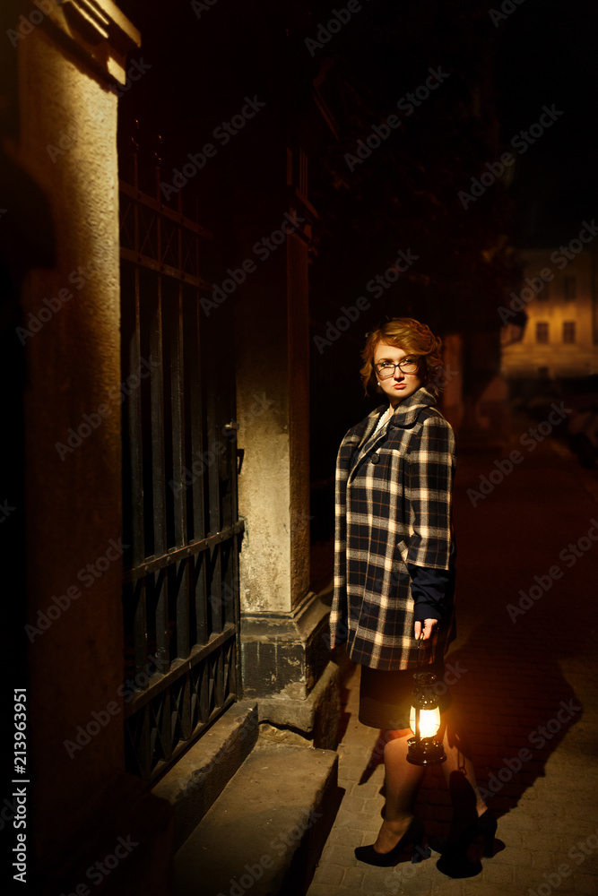 Beautiful blonde woman detective in stylish retro coat holding old lantern, french noire atmosphere concept Beautiful blonde woman detective in stylish retro coat holding old lantern, french noire atmosphere concept