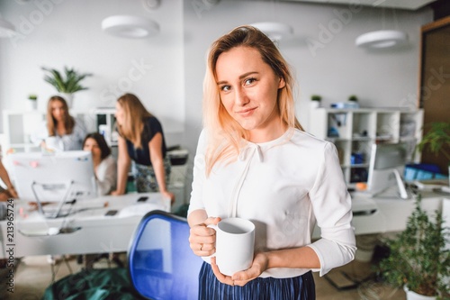 Beautiful girl with a glass of coffee standing in the office