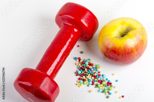 top view of Fitness dumbbell with apple and colorful round pills