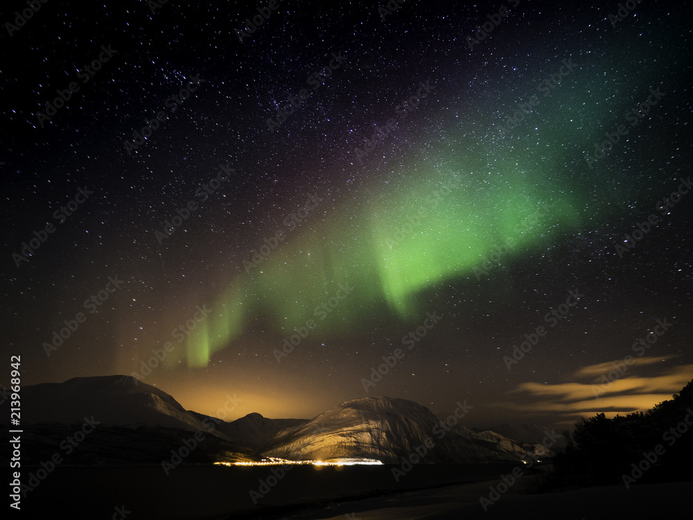 Northern light dancing across starry sky in Norway