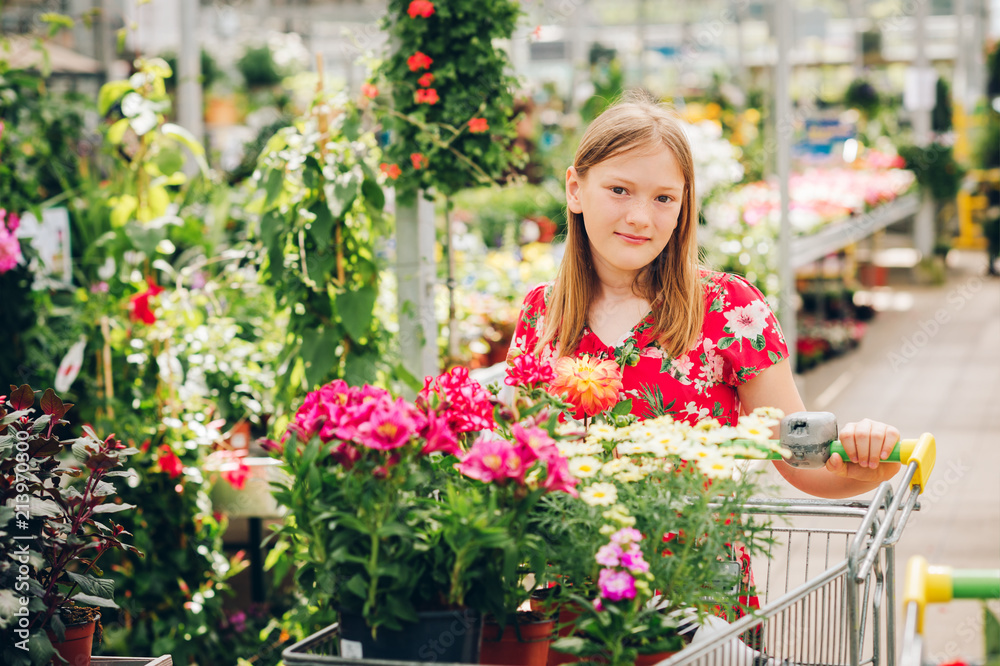 Adorable little girl choosing flowers in garden center