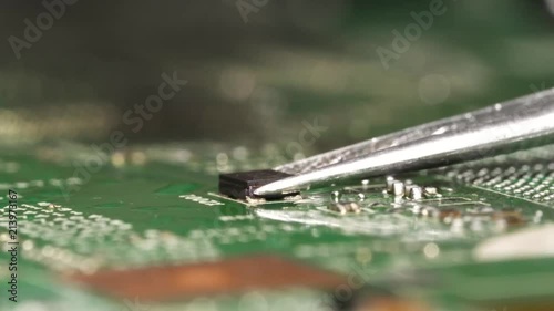 Desolder of small electronic microchip using hot air soldering station and tweezers from the circuit board. Closeup macro. photo