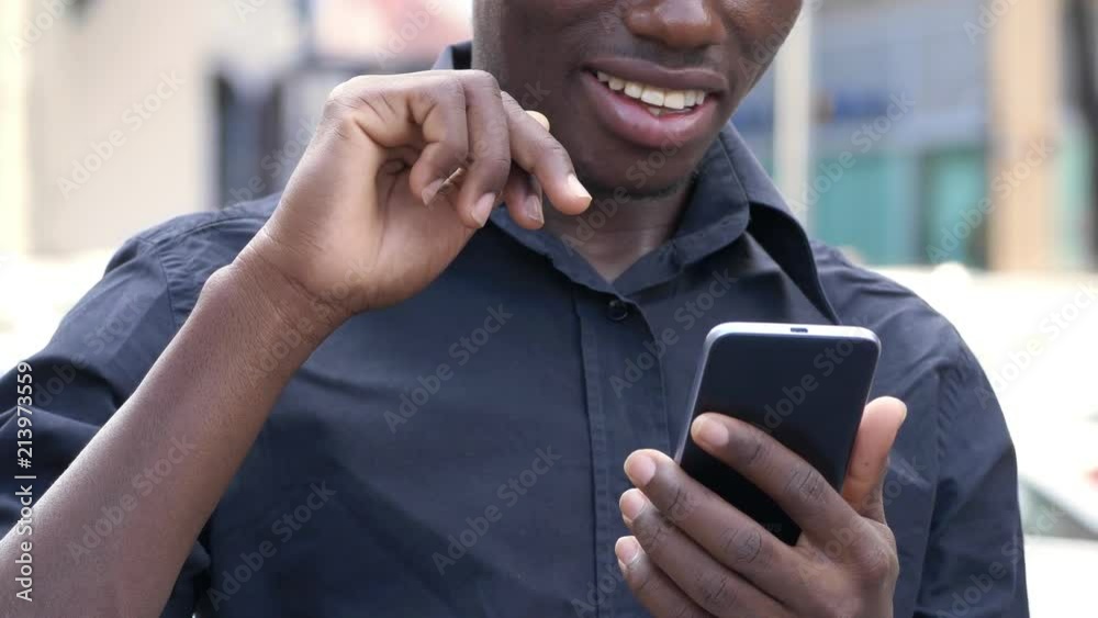 young african man scrolling on smartphone outdoor- slow motion
