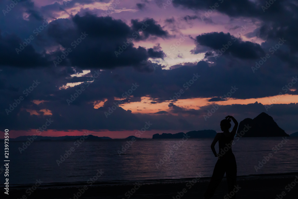 Fototapeta premium Lady in silhouette do yoga with Twilight sky colorful and cloudy over the beach on background