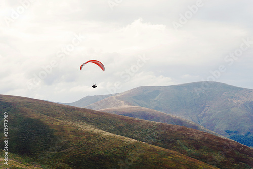 parachute skydiver flying in clouds at mountains, travel adventure concept, space for text