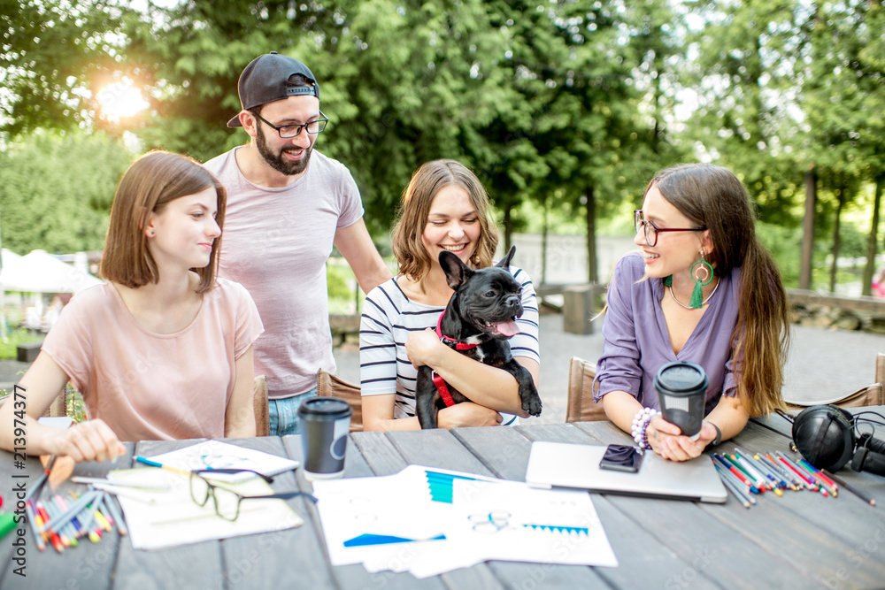 Friends having fun together sitting with dog during a study outdoors at the park cafe Friends having fun together sitting with dog during a study outdoors at the park cafe