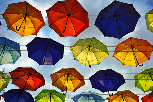 Colorful umbrellas floating above the street on a blue sky