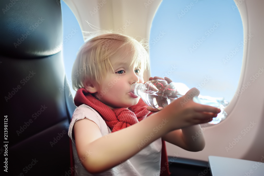 Little boy sitting by aircraft window during the flight