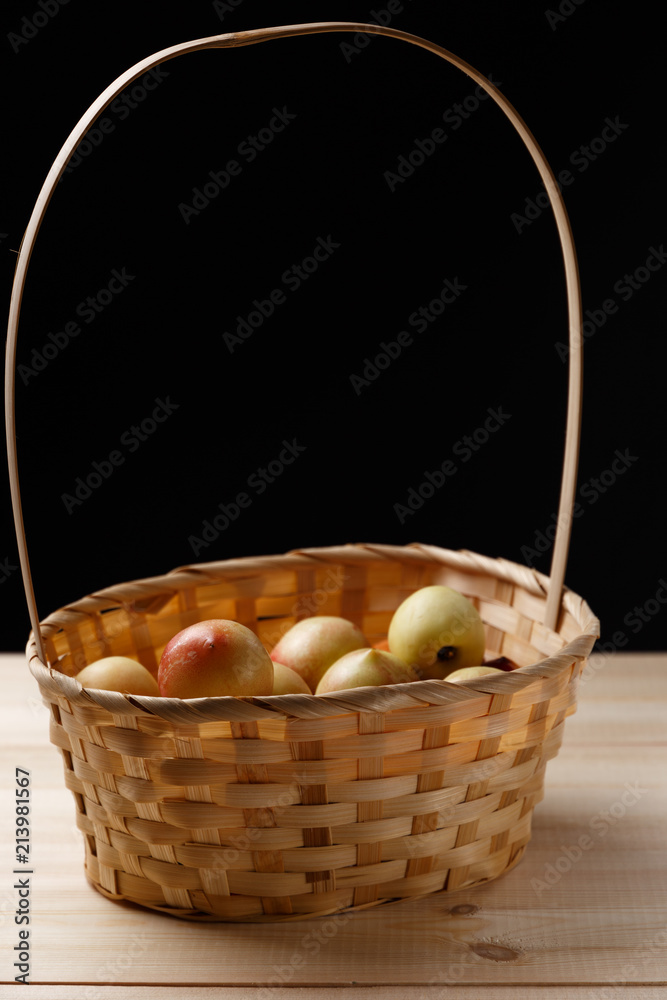 nectarines in a wicker basket on a wooden table