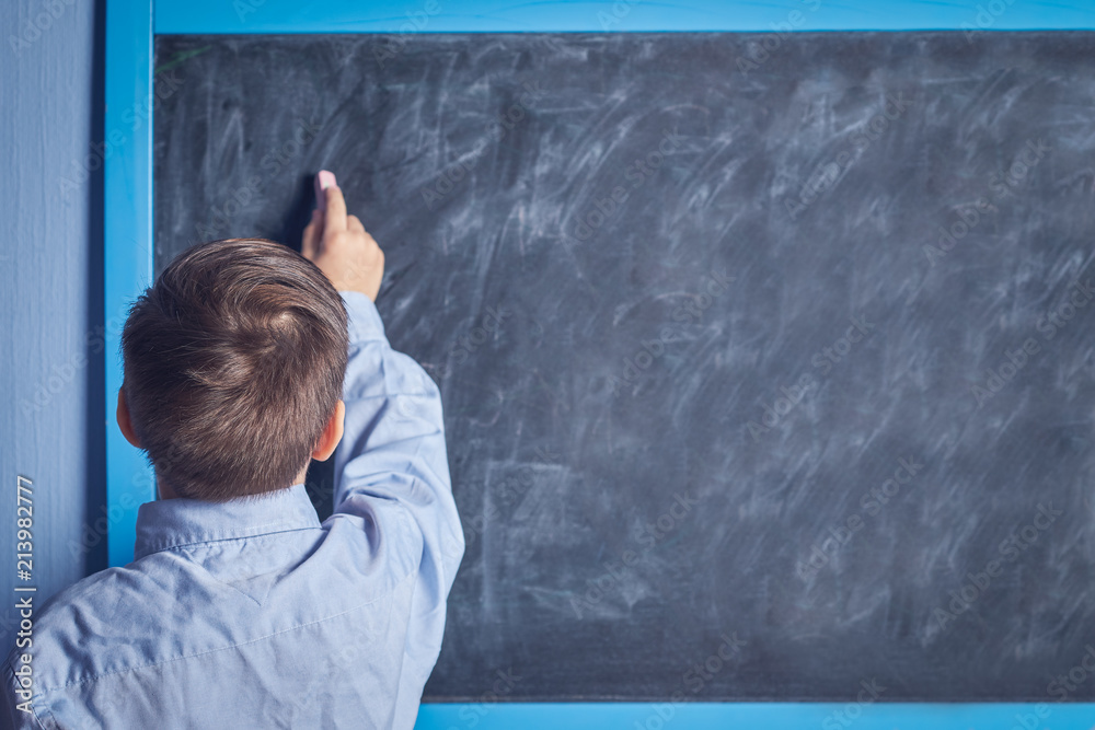 European schoolboy doing task at a blackboard. Back view. European schoolboy doing task at a blackboard. Back view.
