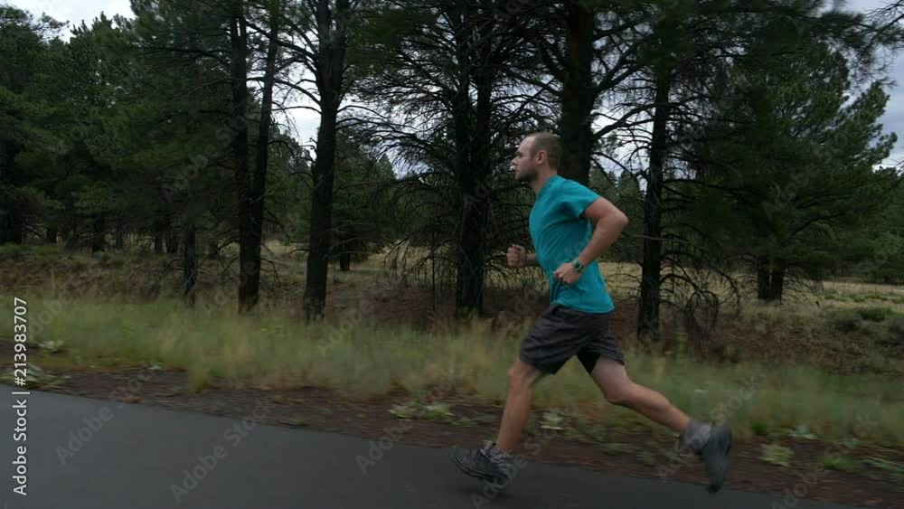Side tracking view of a man running on a country road Side tracking view of a man running on a country road