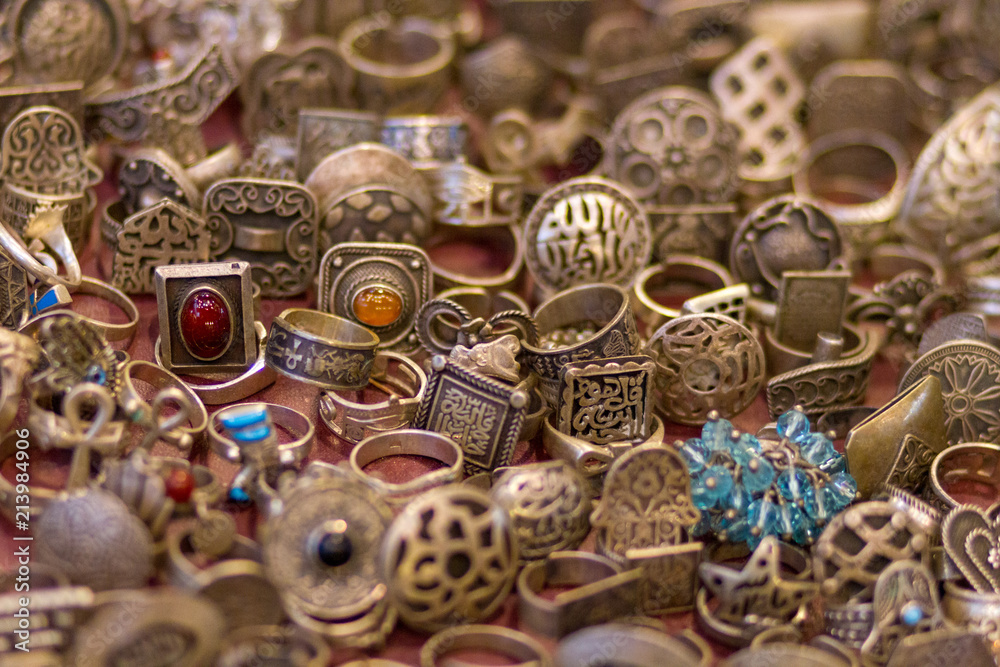 Many old rings made out of silver lying on red cloth ready for sale. Some are set with semi-precious stones