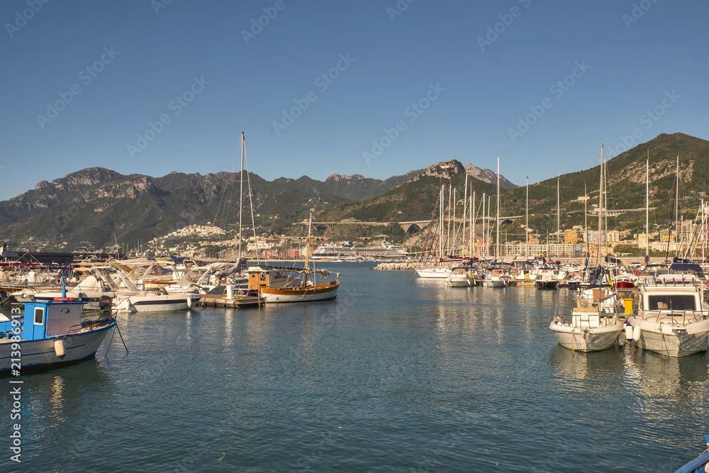 View of the busy harbor at sunrise with ships and containers on the dock. Amalfi Coast. Region Campania, Italy
