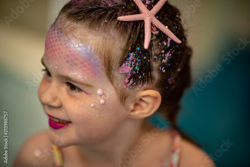 Portrait of a beautiful young mermaid girl at salon getting makeup on