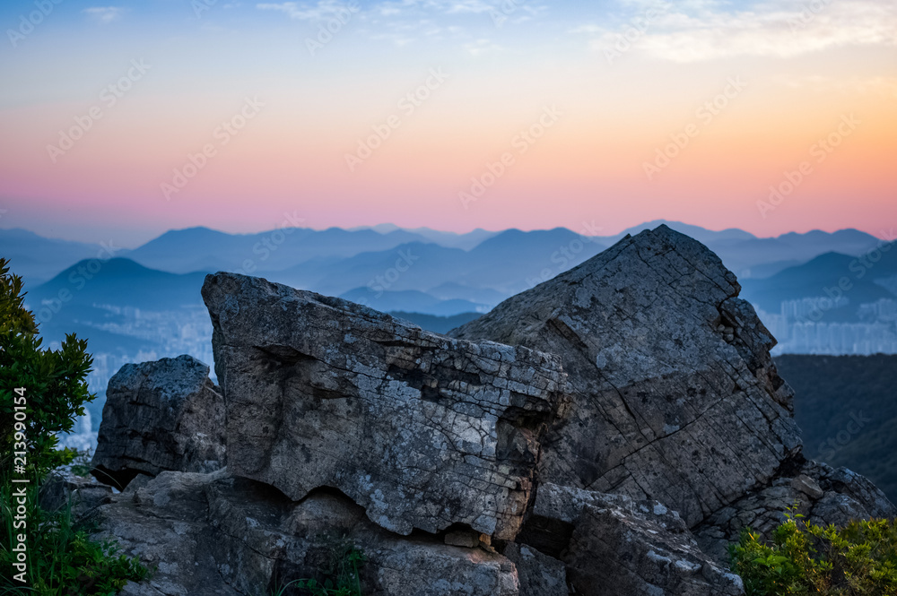 Stacked mountains and orange sky are behind the rocks Stacked mountains and orange sky are behind the rocks