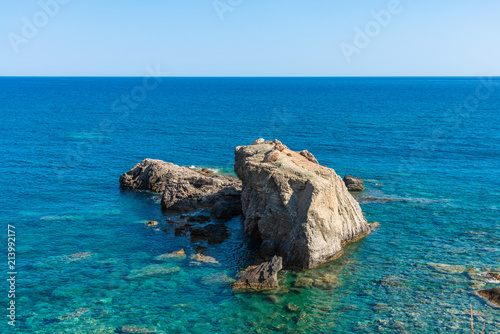 Crystal clear turquoise blue ocean waters. South east coastline with pebble stones and rocks, Grete Greece. Travel vacation concept. photo