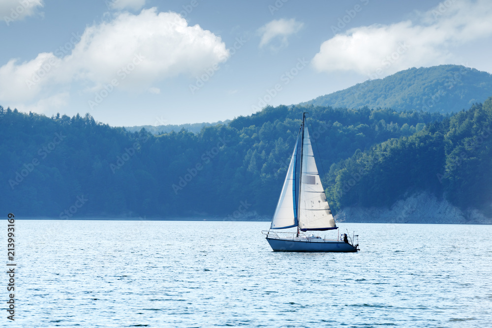 Obraz premium White yacht on Solina lake, Poland. Landscape photography