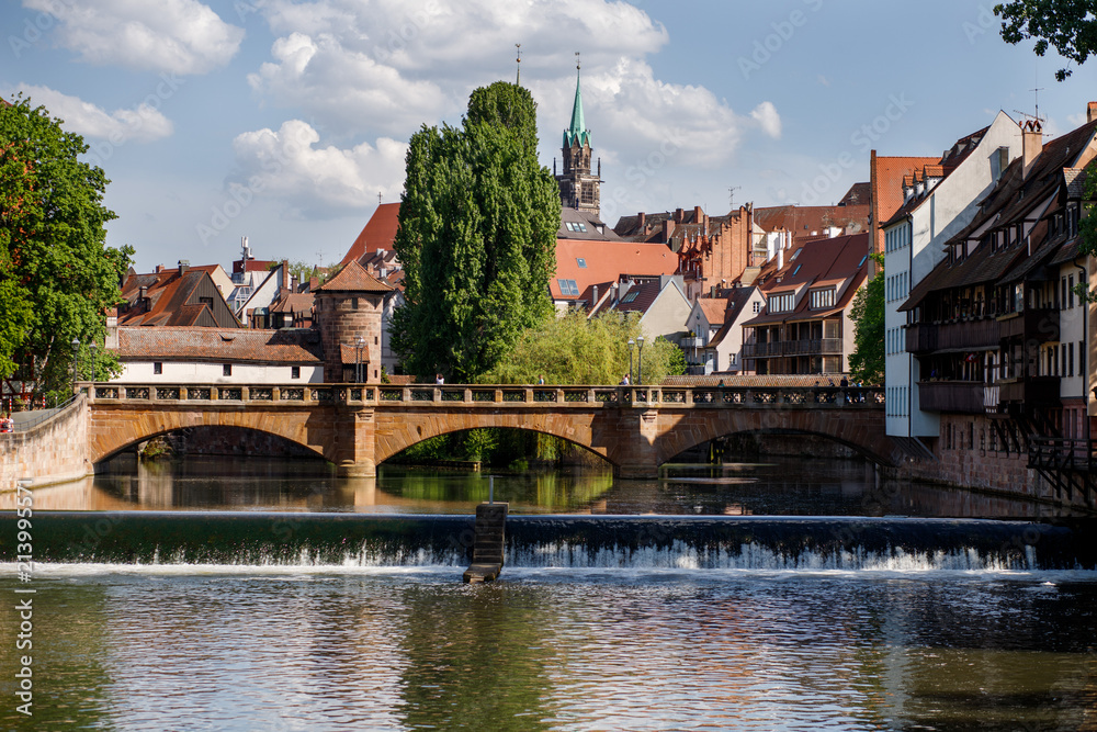 Bridge over the Pegnitz river with a traditional half-timbered house and tower on the riverbank in the Old town of Nuremberg, Bavaria, Germany.