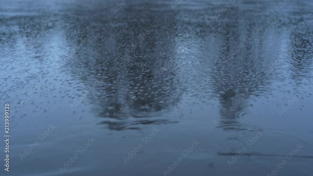Frozen lake with a thin ice in the winter while it's raining