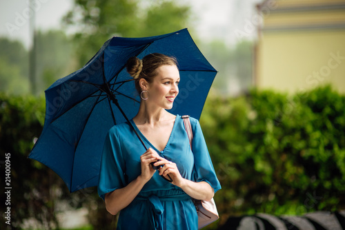 Young girl with blue umbrella . Summer rain
