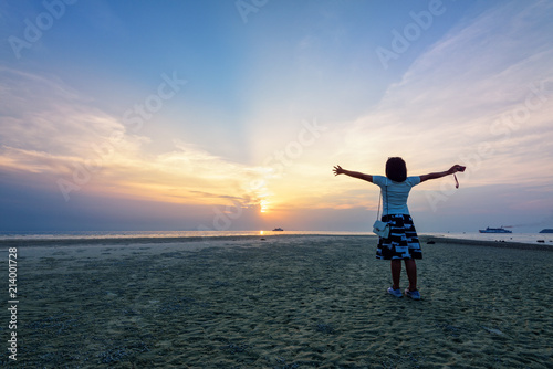 Happy woman tourist arms outstretched on the beach watching the beautiful natural landscape of colorful sky and sea during sunset at Nathon Sunset Viewpoint in Samui island, Surat Thani, Thailand © yongkiet