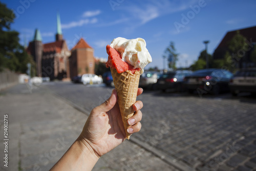 The hand holds ice cream against the backdrop of the sights of the city of Wroclaw. Ostrow Tumski