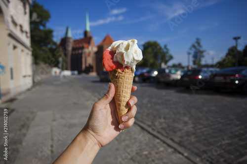 The hand holds ice cream against the backdrop of the sights of the city of Wroclaw. Ostrow Tumski