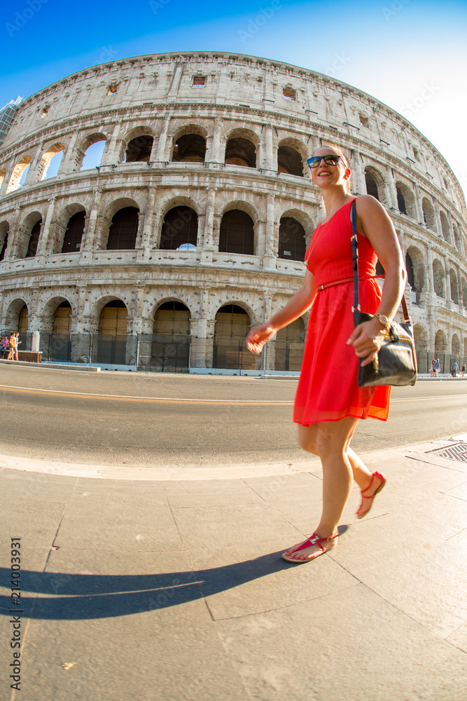 Junge Frau spaziert am colosseum in Rom im roten kleid und mit einer Handasche