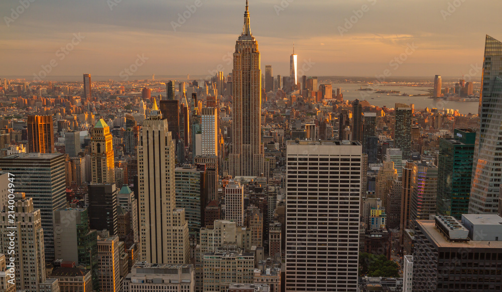 View of Manhattan skyline at sunset or golden hour. Buildings are bathed in golden light.