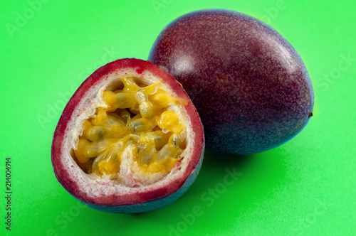 Tropical fruits and exotic foods concept with passion fruit or granadilla slice open, isolated on green background