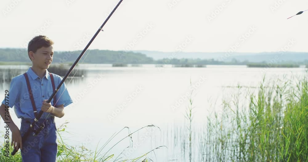 Teen pretty boy fishing on the river and catching a fish on the rod in the very beautiful landscape. Outside. Teen pretty boy fishing on the river and catching a fish on the rod in the very beautiful landscape. Outside.