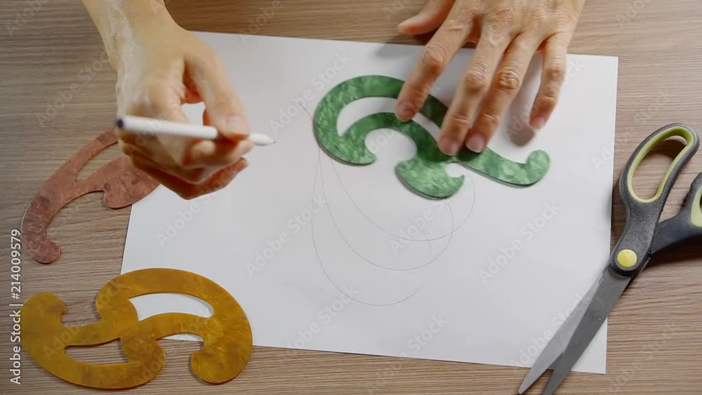 Woman drawing interesting traceries on paper with pencil.