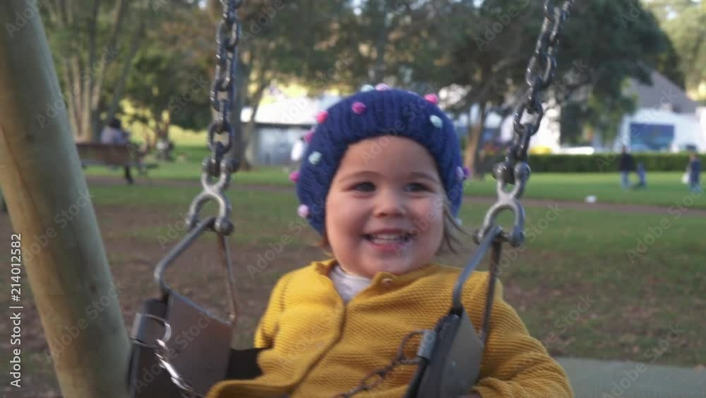 Little girl having fun smiling on swing with mother in park. Toddler swinging in Slow Motion. Little girl having fun smiling on swing with mother in park. Toddler swinging in Slow Motion.